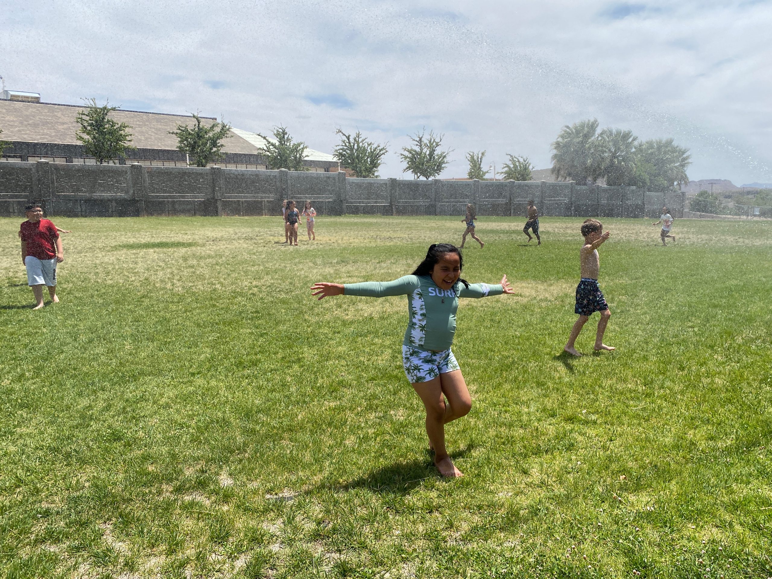 Students having fun playing in the sprinklers on the field