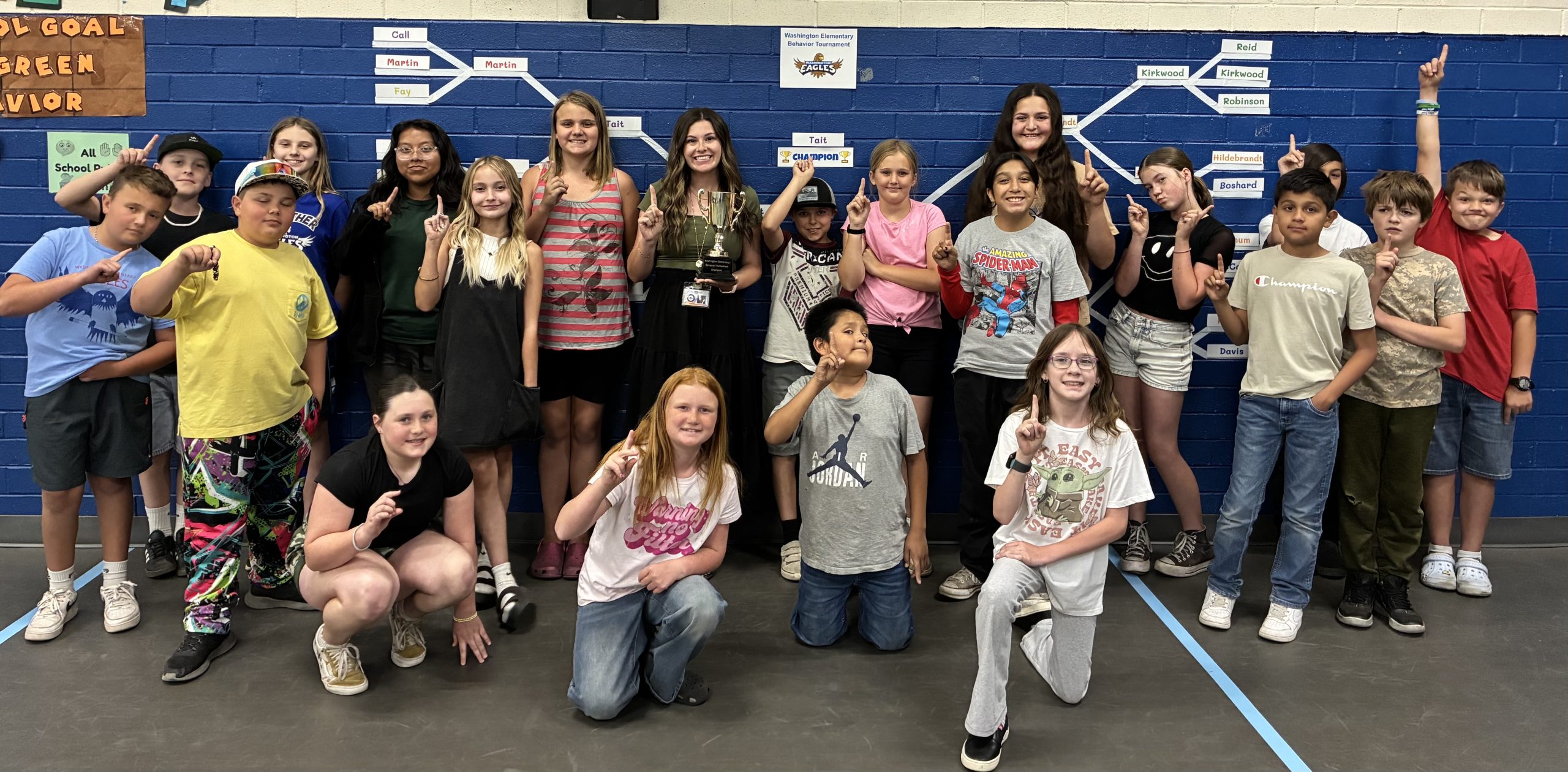 Mrs. Tait's class smiling in front of the behavior tournament bracket
