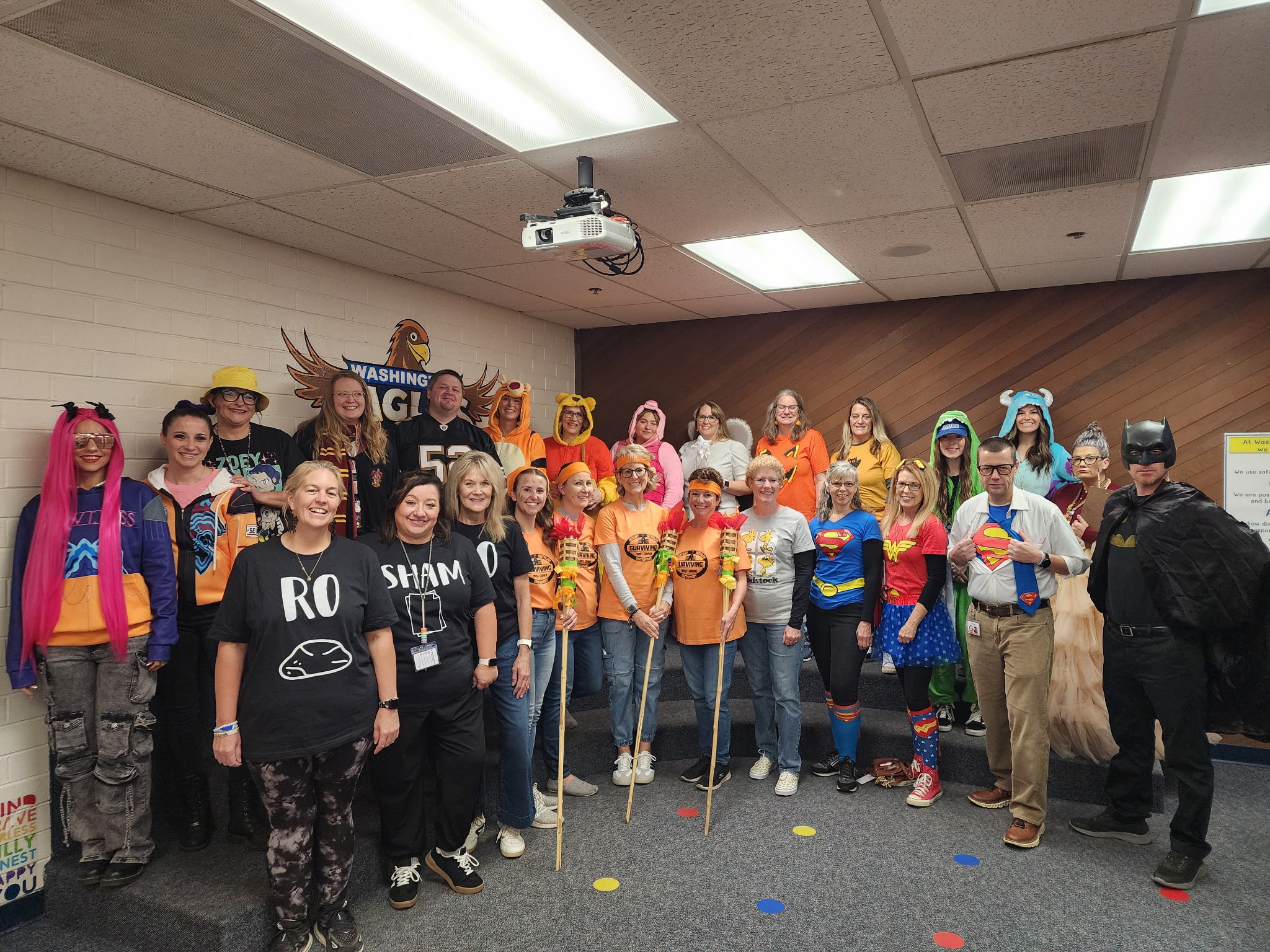 WES staff posing for a picture in the library in their Halloween costumes.