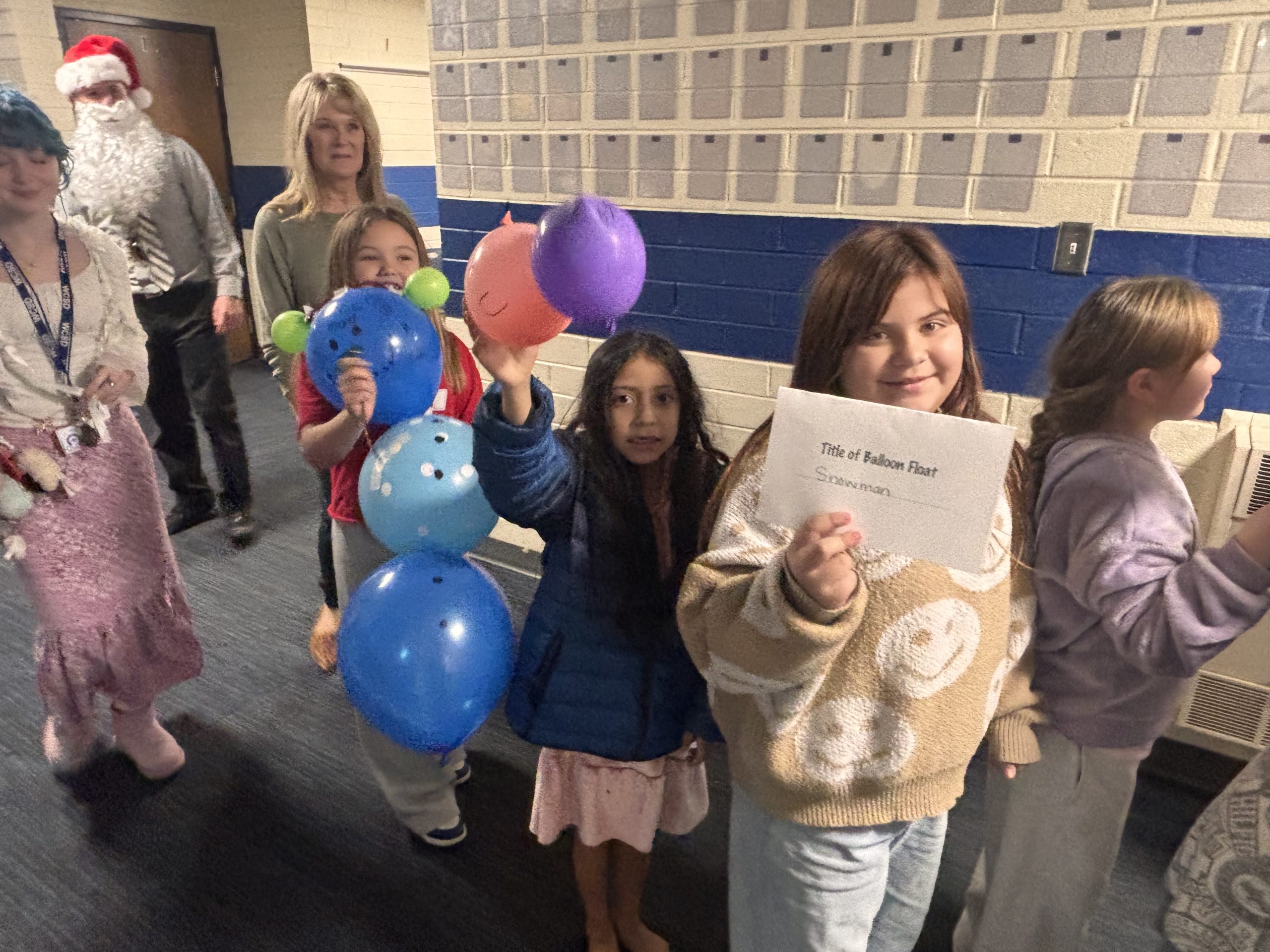 2nd and 3rd grade students walking down the hall holding balloon creations 
