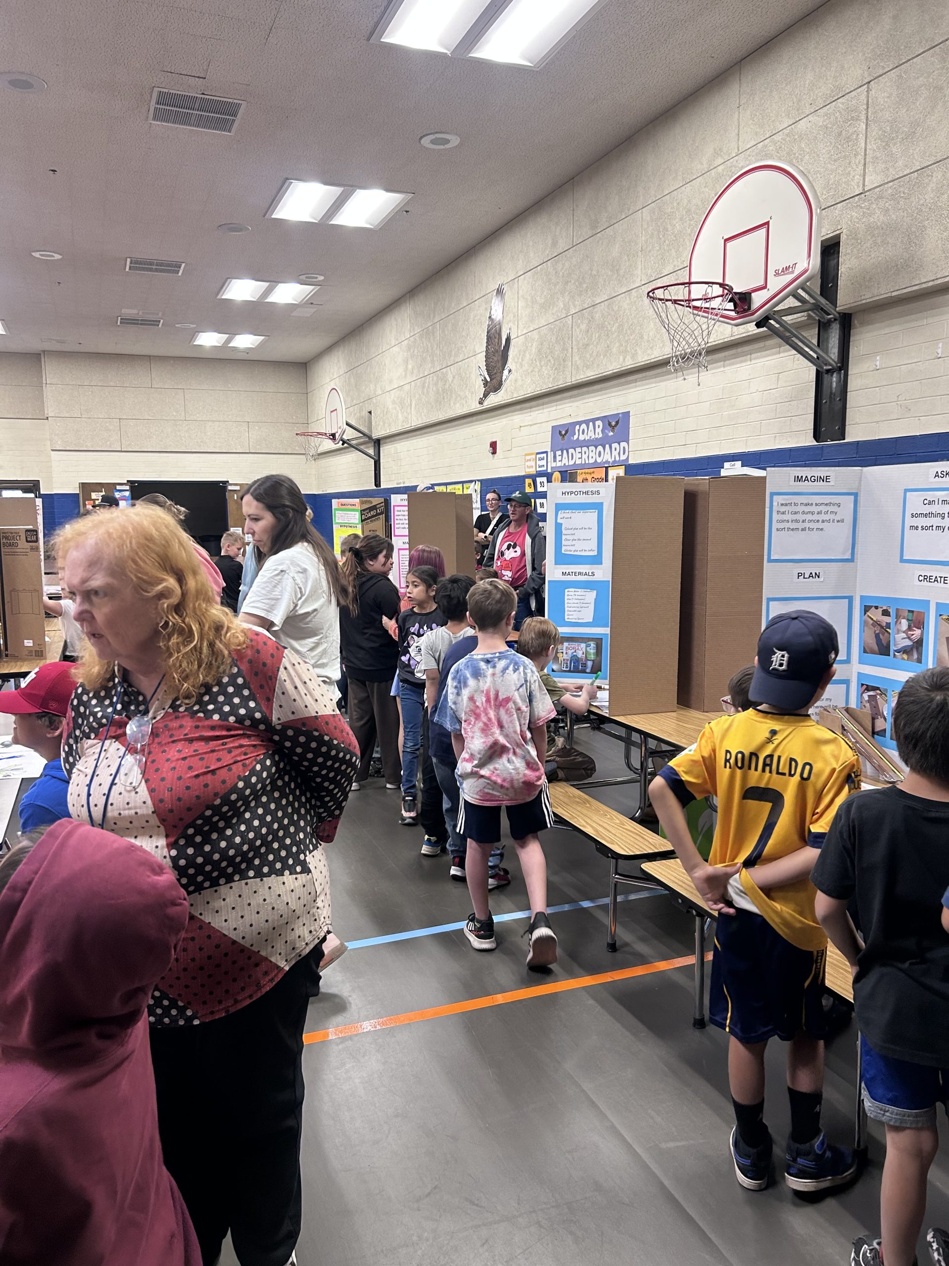 Picture of students, teachers, and parents walking around the lunchroom looking at Science Fair project displays